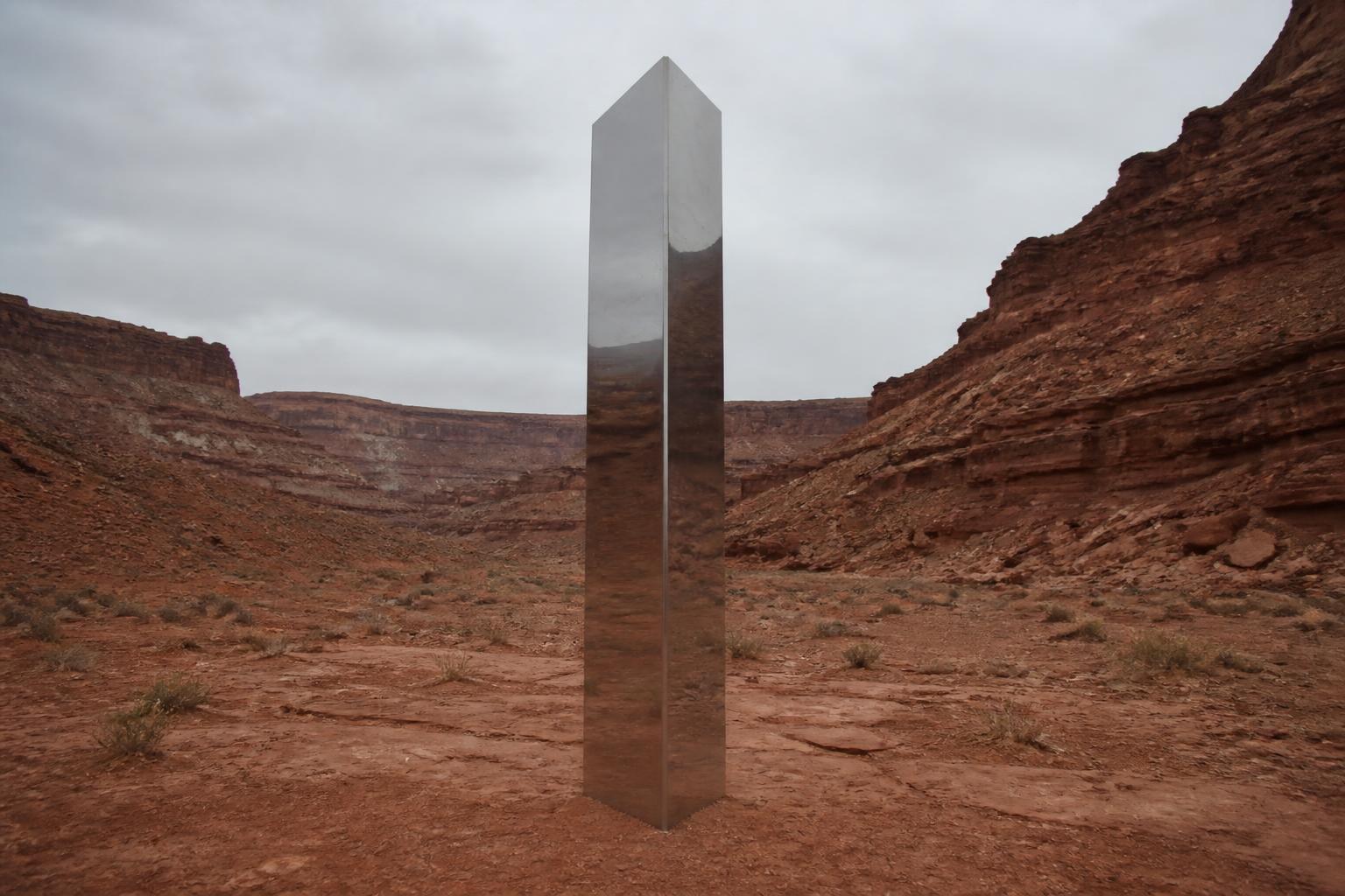 A silent metal monolith standing in a red desert landscape, evoking the 2020 Utah monolith phenomenon.